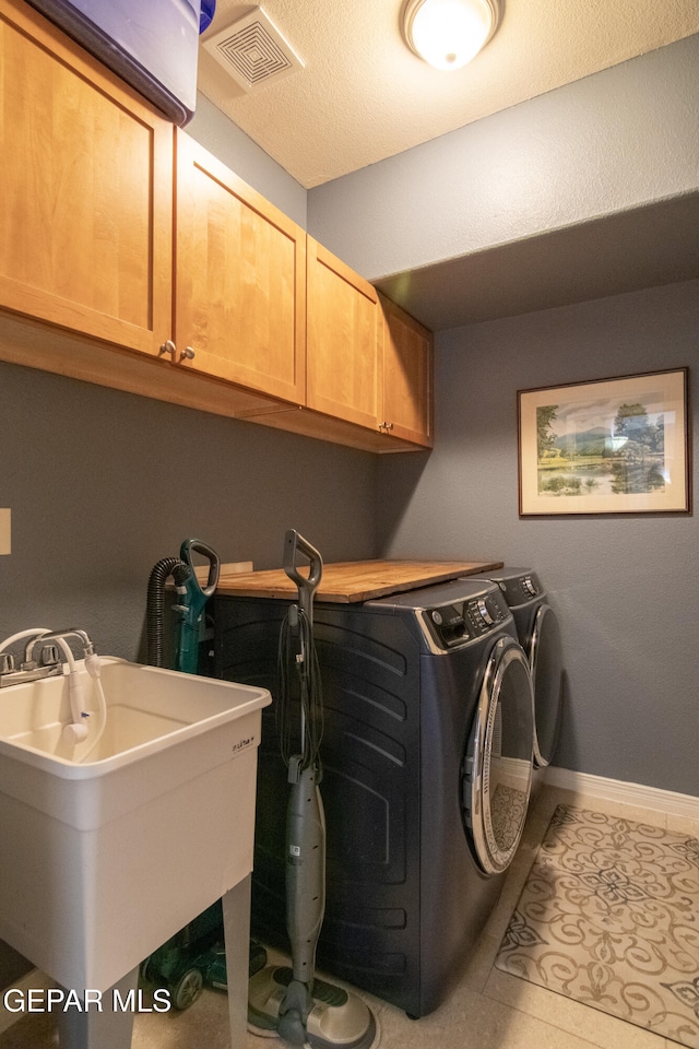 washroom featuring sink, washing machine and clothes dryer, light tile patterned floors, and cabinets