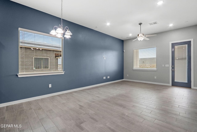 empty room with wood-type flooring and ceiling fan with notable chandelier