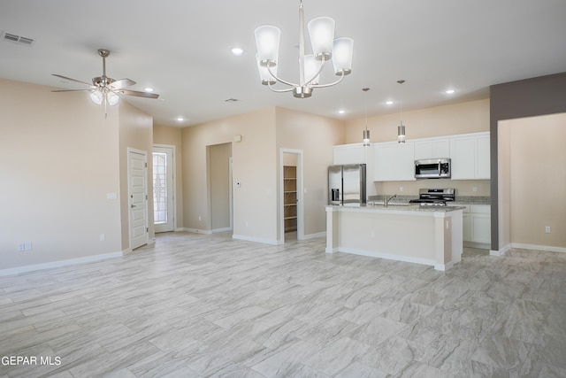 kitchen featuring appliances with stainless steel finishes, an island with sink, white cabinets, and pendant lighting