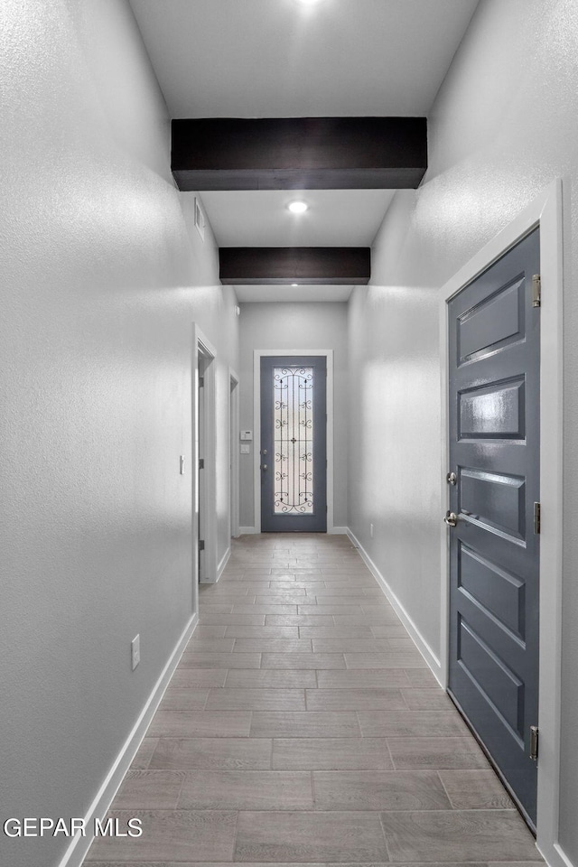 doorway to outside with beam ceiling and light hardwood / wood-style floors