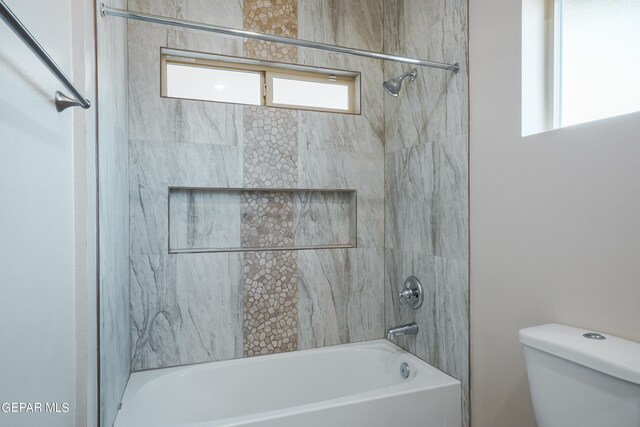 bathroom featuring tiled shower / bath combo and toilet