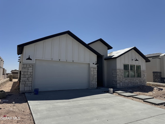 1416 Dylan Pl, El Paso, TX 79928 - view of front facade with board and batten siding, stone siding, a garage, and driveway