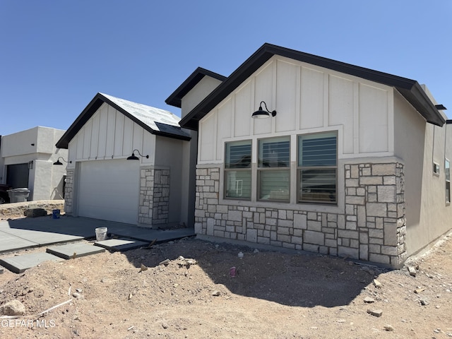 1416 Dylan Pl, El Paso, TX 79928 - view of front of home featuring board and batten siding, stone siding, an attached garage, and driveway