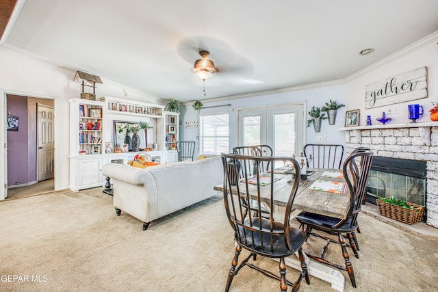 dining area featuring a stone fireplace, light colored carpet, and ceiling fan