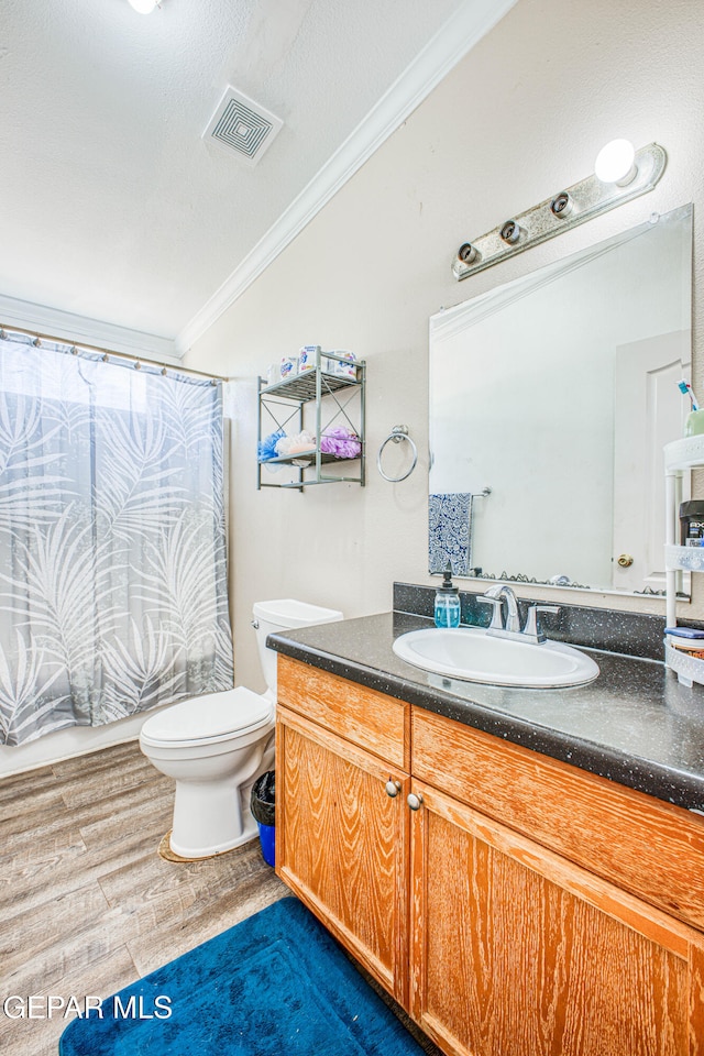 bathroom with vanity, toilet, hardwood / wood-style flooring, and crown molding