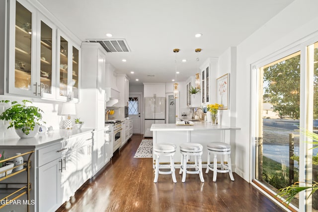 kitchen with a breakfast bar area, backsplash, decorative light fixtures, white refrigerator, and white cabinets