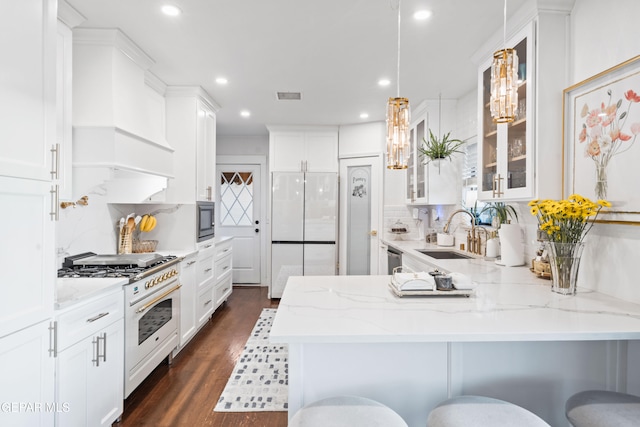 kitchen featuring built in appliances, dark wood-type flooring, a breakfast bar area, and sink