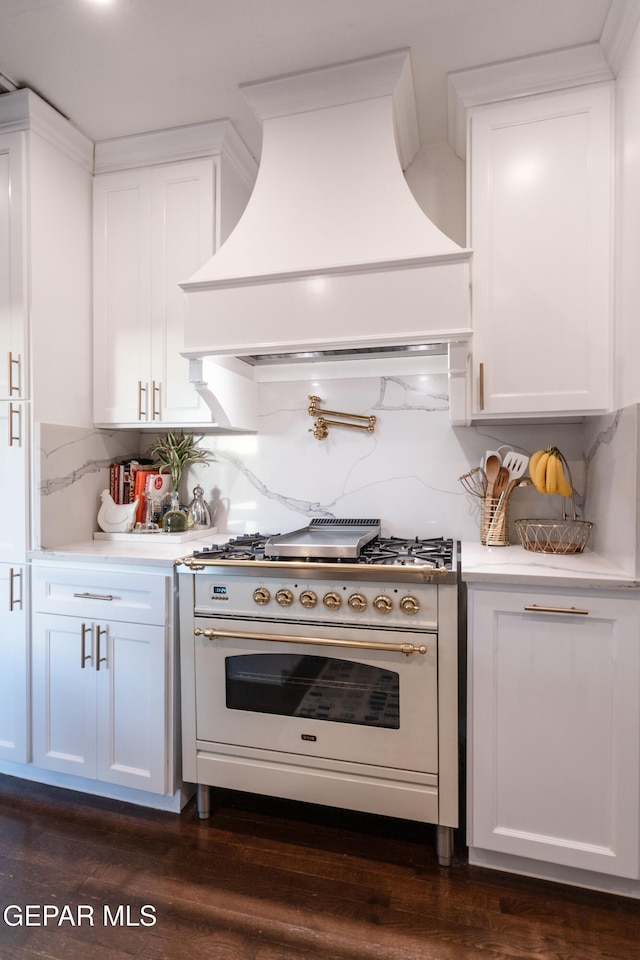 kitchen featuring tasteful backsplash, dark hardwood / wood-style flooring, premium range hood, white cabinetry, and high end white range oven