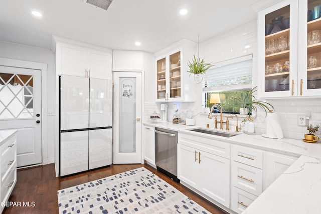 kitchen with white cabinets, light stone countertops, stainless steel dishwasher, white built in fridge, and sink