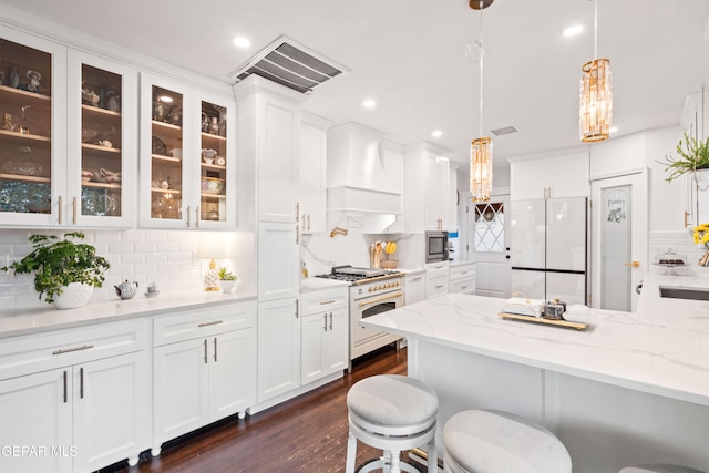 kitchen featuring tasteful backsplash, light stone countertops, appliances with stainless steel finishes, pendant lighting, and a breakfast bar area