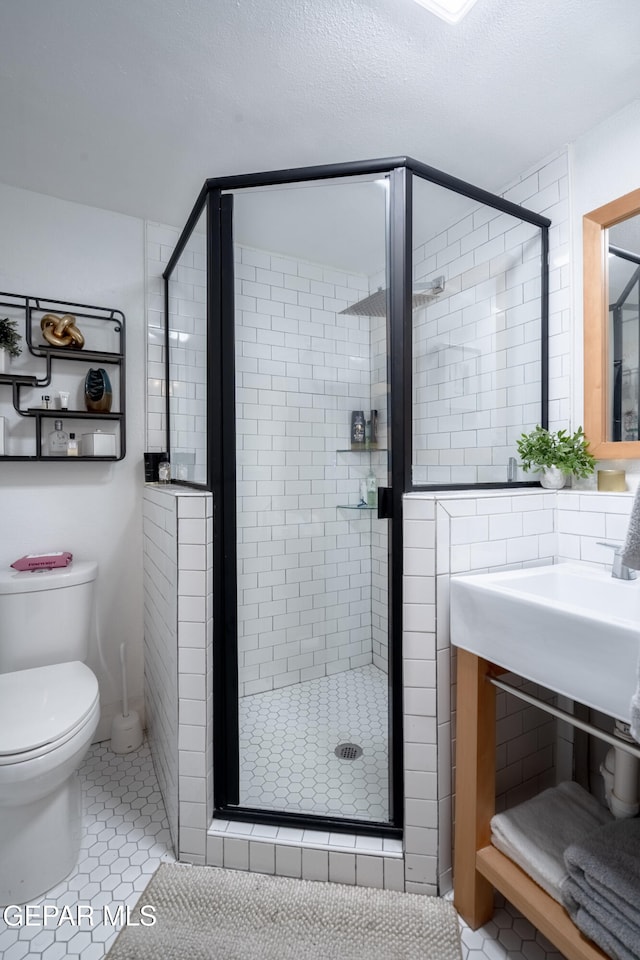 bathroom featuring a textured ceiling, tile patterned flooring, toilet, and walk in shower