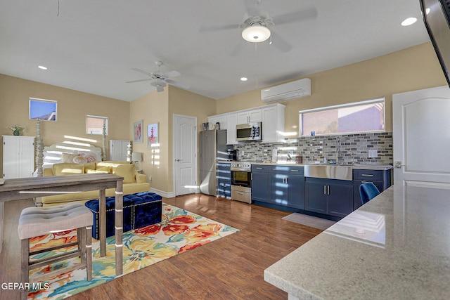 kitchen with a wall mounted AC, backsplash, blue cabinetry, dark hardwood / wood-style floors, and stainless steel appliances