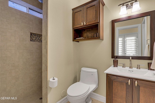 bathroom featuring toilet, vanity, and a tile shower