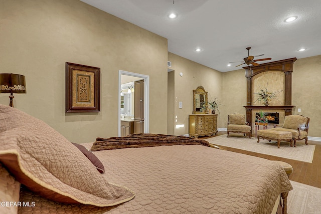 bedroom with connected bathroom, ceiling fan, and hardwood / wood-style flooring