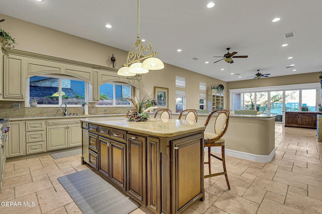 kitchen with backsplash, a breakfast bar, a center island, sink, and decorative light fixtures