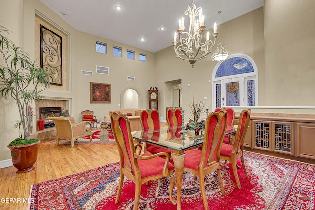 dining space with light hardwood / wood-style floors, an inviting chandelier, and a towering ceiling