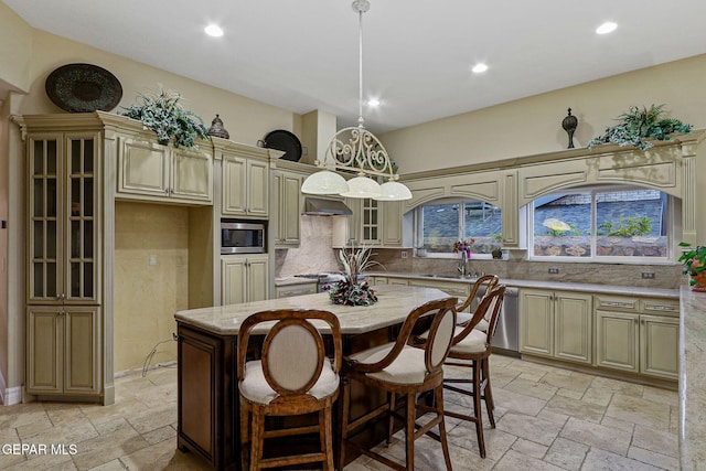 kitchen featuring a kitchen island, decorative backsplash, cream cabinetry, stainless steel appliances, and sink