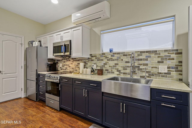 kitchen with white cabinets, backsplash, a wall mounted air conditioner, dark wood-type flooring, and stainless steel appliances