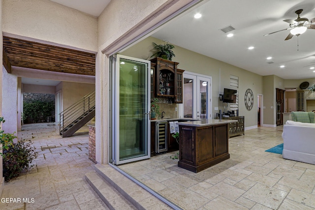 kitchen with a kitchen island, dark brown cabinets, sink, beverage cooler, and ceiling fan