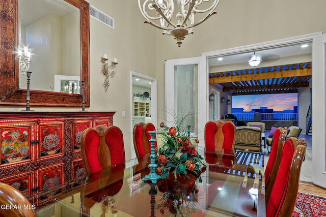 dining space featuring a notable chandelier, hardwood / wood-style flooring, and a high ceiling