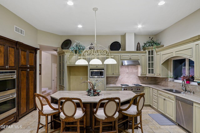 kitchen with cream cabinets, stainless steel appliances, sink, and pendant lighting