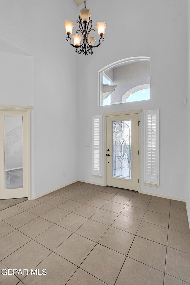 foyer entrance featuring a notable chandelier, a high ceiling, and light tile patterned flooring