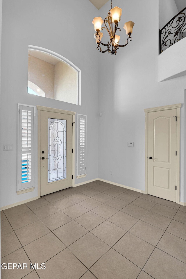 tiled entrance foyer with a notable chandelier and a towering ceiling