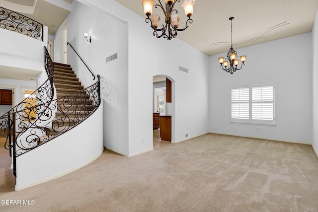 interior space featuring an inviting chandelier, light colored carpet, and a high ceiling