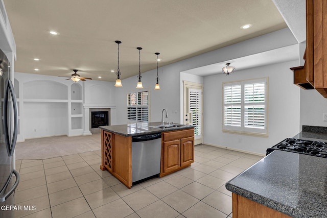 kitchen with hanging light fixtures, ceiling fan, an island with sink, sink, and stainless steel appliances