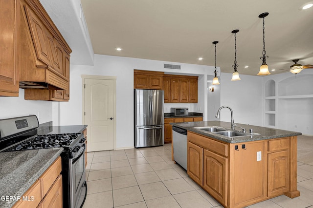 kitchen featuring light tile patterned floors, stainless steel appliances, sink, and an island with sink