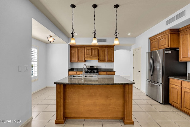 kitchen with an island with sink, hanging light fixtures, stainless steel appliances, sink, and light tile patterned flooring