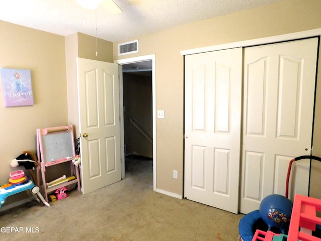 recreation room featuring light colored carpet and a textured ceiling