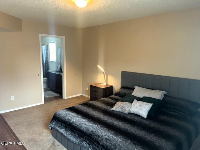 carpeted bedroom featuring ensuite bath and a textured ceiling