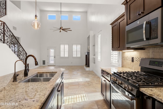 kitchen with plenty of natural light, dark brown cabinetry, stainless steel appliances, and light stone counters