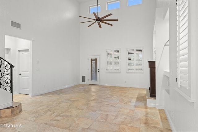 unfurnished living room featuring a high ceiling and ceiling fan