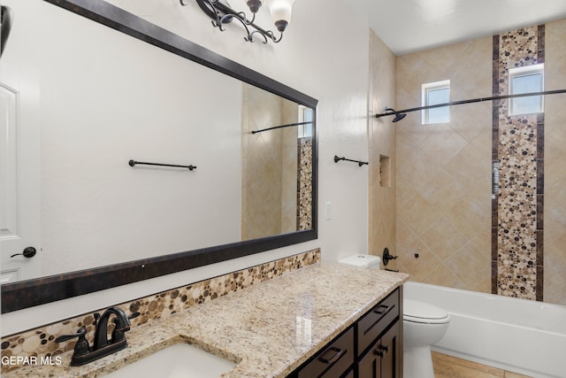 full bathroom featuring tiled shower / bath, vanity, and toilet