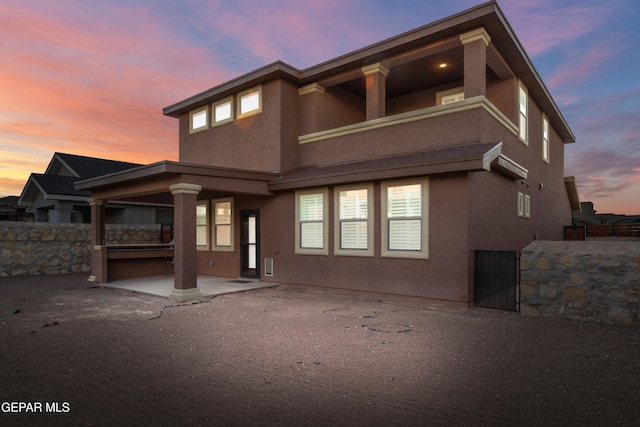 back house at dusk featuring a balcony