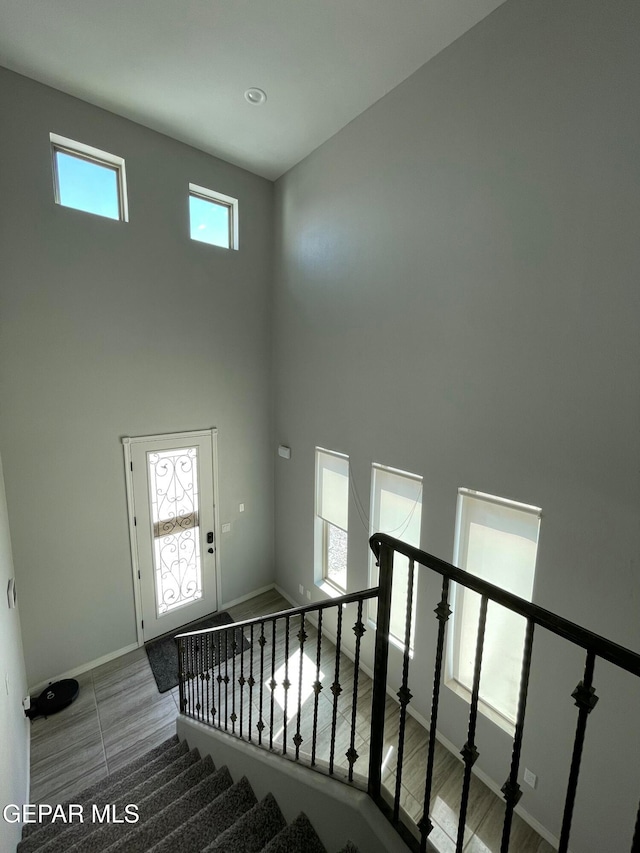 stairs with a high ceiling, wood-type flooring, and plenty of natural light