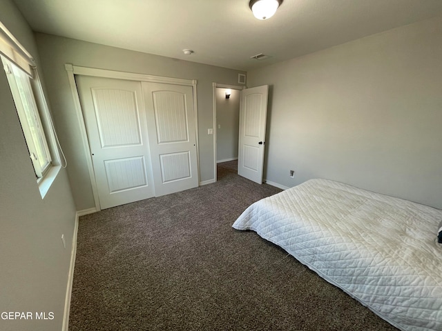 bedroom with a closet and dark carpet