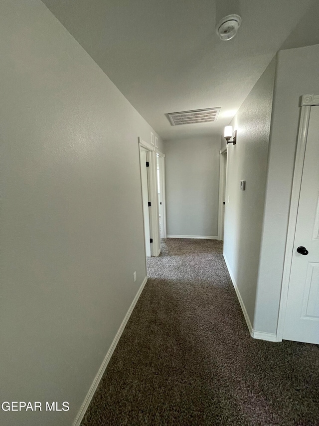 hall with dark colored carpet