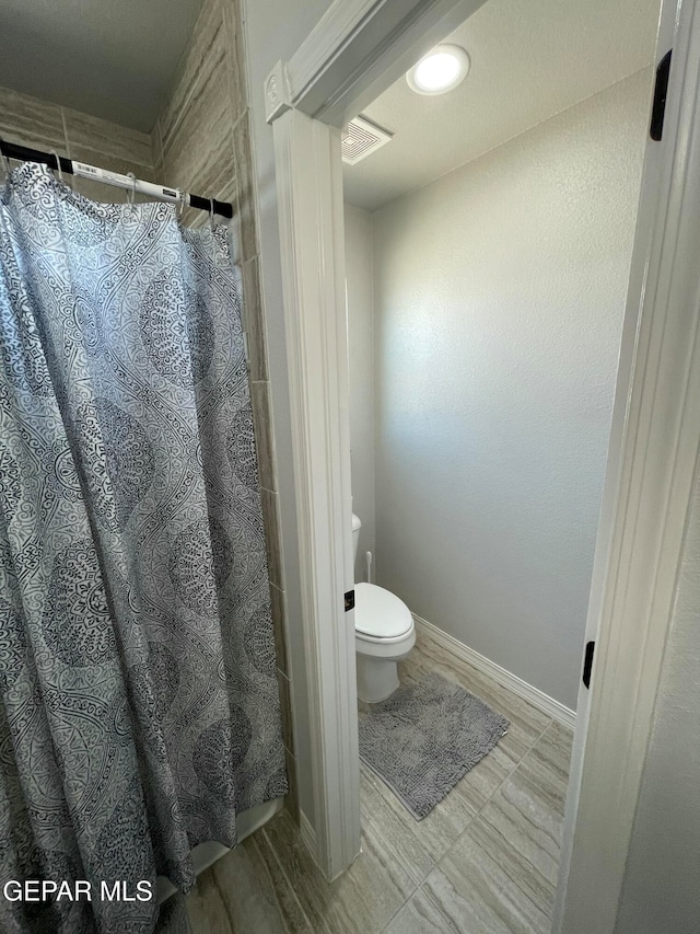 bathroom featuring toilet and a shower with shower curtain