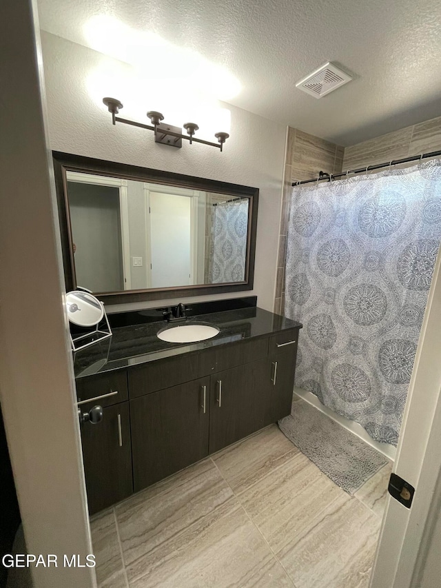 bathroom with vanity, a textured ceiling, and walk in shower