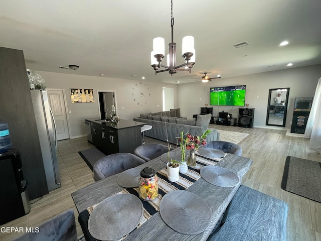 dining room with sink and ceiling fan with notable chandelier