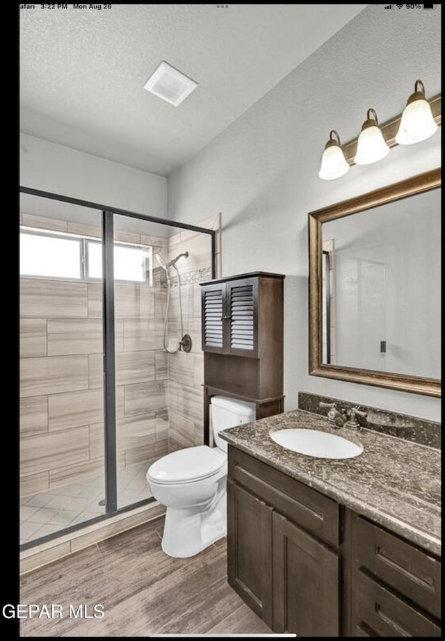 bathroom featuring a textured ceiling, an enclosed shower, toilet, vanity, and hardwood / wood-style flooring