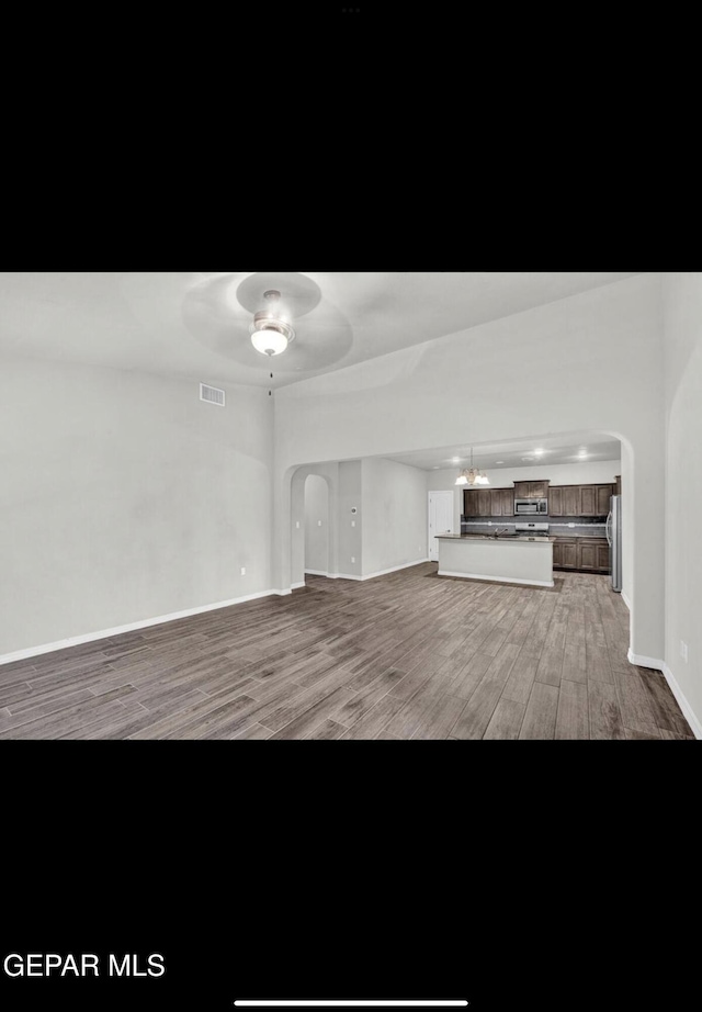 unfurnished living room featuring ceiling fan and hardwood / wood-style flooring