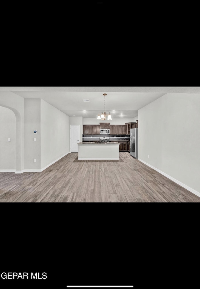 unfurnished living room featuring a chandelier and light wood-type flooring