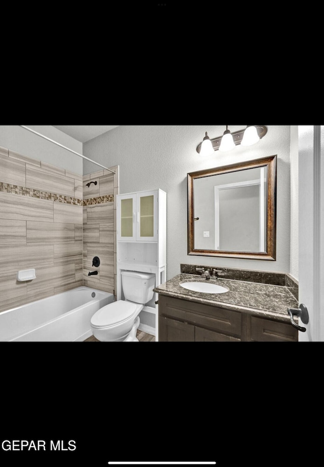 full bathroom featuring tiled shower / bath, vanity, and toilet