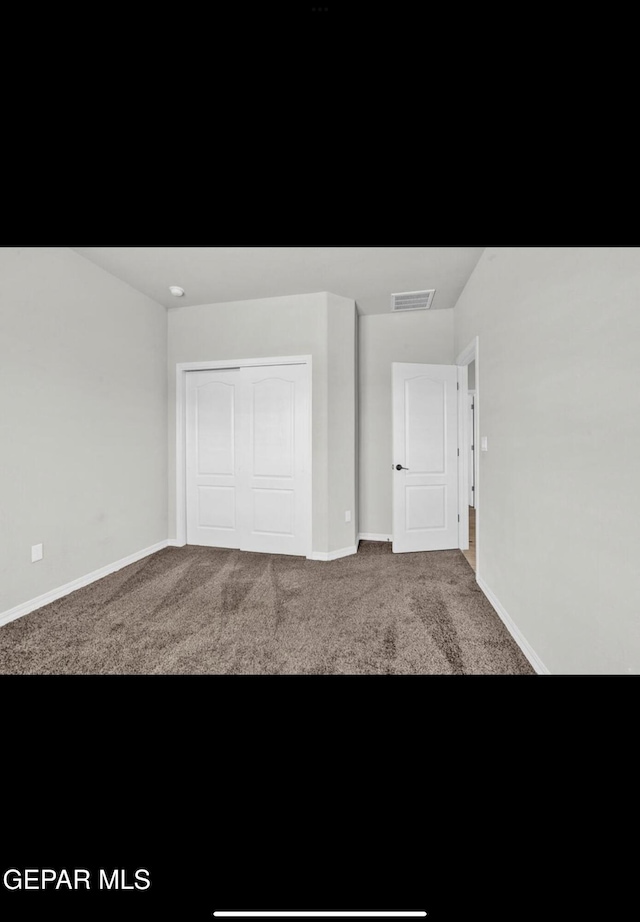 unfurnished bedroom featuring carpet and a closet