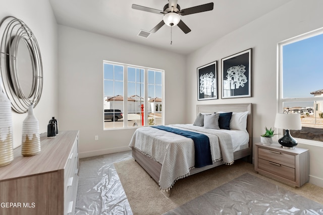 bedroom with ceiling fan, light carpet, and multiple windows