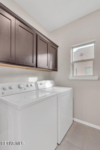 laundry area with independent washer and dryer, light tile patterned floors, and cabinets